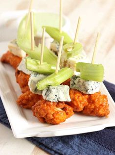 chicken skewers with celery and blue cheese on a white square plate