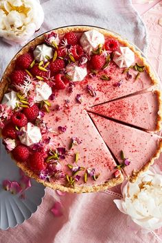 a pie with strawberries and whipped cream on top sits on a pink tablecloth