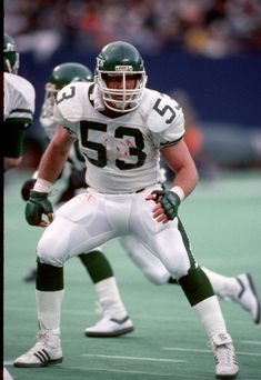 a football player kneeling on the field during a game with other players in the background