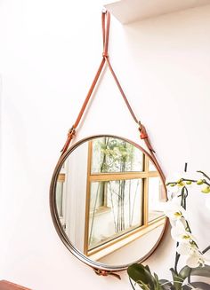 a mirror hanging on the side of a wall next to a vase with flowers in it