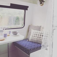 a small table with two cups on it next to a window in a camper