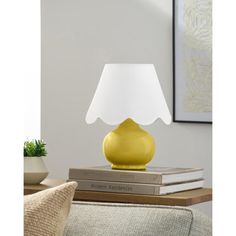 a yellow table lamp sitting on top of a stack of books next to a couch