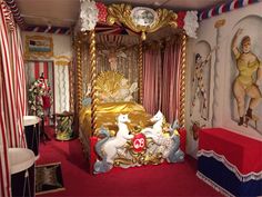 an elaborately decorated bedroom with red carpet and gold canopy bed in the center, surrounded by circus decorations