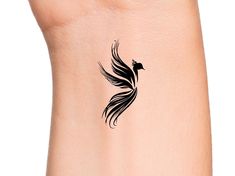 a small black bird tattoo on the side of a woman's right arm and wrist