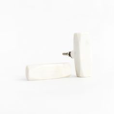 a pair of white ceramic knobs sitting next to each other on a white surface