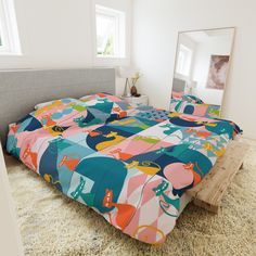 the bed is made with colorful comforters and pillows, along with a mirror on the wall