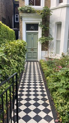 a black and white checkerboard walkway leading to a green door in a house