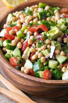 a wooden bowl filled with cucumber, chickpeas and red onion salad