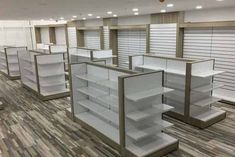 empty shelves in a store with wooden flooring and white shelvings on the walls