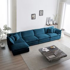 a living room with a large blue couch and coffee table in front of the window