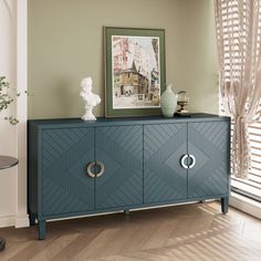 a blue cabinet with two doors and some vases on top of it in front of a window