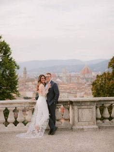 a bride and groom pose for a photo in front of the city