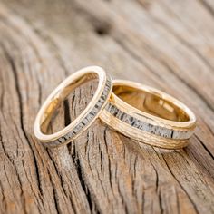 two wedding rings sitting on top of a wooden table