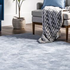 a living room with a blue couch, chair and rug on the floor in front of it