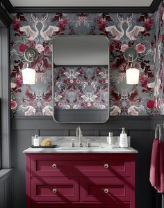 a bathroom with red cabinets and floral wallpaper on the walls, along with a large mirror