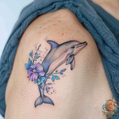 a dolphin with flowers on it's back is shown in this tattoo design by the artist