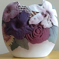 a vase with flowers painted on it sitting on a table