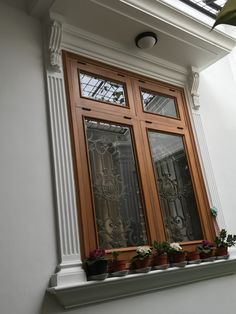 a window with potted plants in front of it on the side of a building