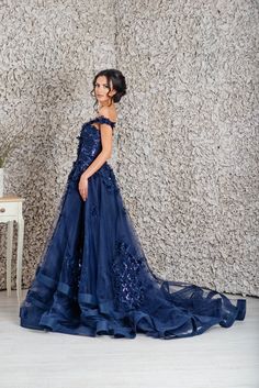 a woman standing in front of a wall wearing a blue dress with sequins on it