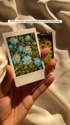 a person holding up a polaroid with flowers on it