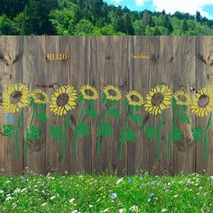 a wooden fence with sunflowers painted on it and the word hello written in green