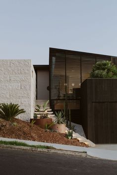 a modern house with plants in the front yard