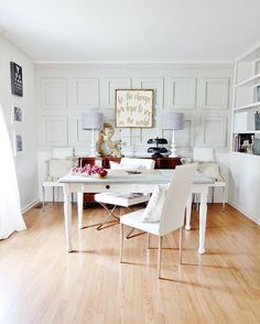 a dining room with white chairs and wood flooring