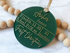 a green ornament with names and dates on it sitting next to some wood beads