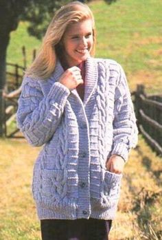 a woman is standing in the grass wearing a cardigan