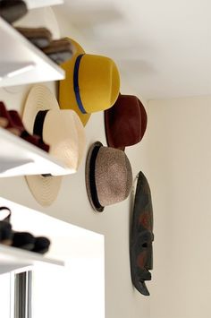 hats are hanging from the ceiling in a room with white walls and open shelving