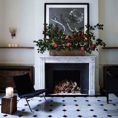 a living room with a fireplace and flowers on the mantel above it, next to a black chair