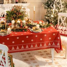 a christmas table setting with candles, plates and decorations on the table in front of a fireplace