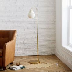 a brown leather chair sitting next to a lamp on top of a hard wood floor