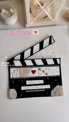 a white table topped with a black and white movie clapper next to a box filled with candy