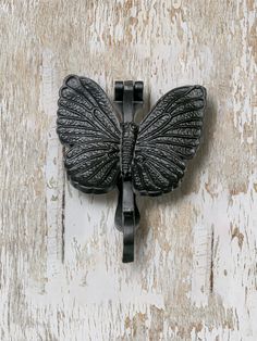 a black butterfly shaped hook on a white wooden wall