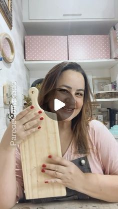 a woman holding a wooden cutting board in front of her face and smiling at the camera