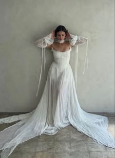 a woman in a white dress with her hands on her head and arms behind her head