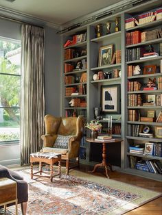 a living room filled with lots of furniture and bookshelves next to a window