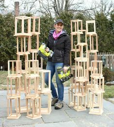 a woman standing in front of stacks of wooden blocks and holding a pair of drillers