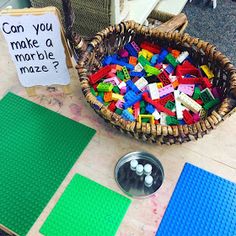 a basket full of legos sitting on top of a table next to a sign that says can you make a marble maze?