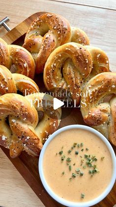 several pretzels on a wooden tray with a bowl of dip and breadsticks