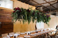 the table is set with white plates and place settings, hanging from wood planks