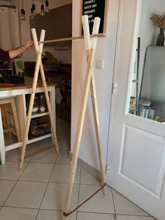 a woman standing next to a wooden easel on top of a tile floor in front of a white door