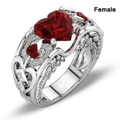 a red heart shaped ring with diamonds on the sides and two hearts in the middle