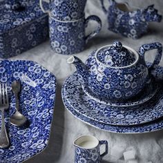 a blue and white dinner set with silverware on the tablecloth, ready to be eaten