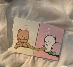 two small cards with teddy bears on them sitting on a white bed sheet, next to each other