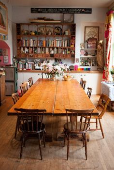 an old fashioned dining room table and chairs with bookshelves in the background,