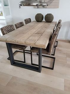 a wooden table with chairs and vases on it in a room that has hardwood floors