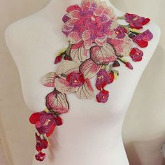 a white mannequin with pink and red flowers on it's neckline