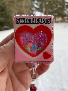 "Celebrate Valentine's Day with this unique Shaker 3D  bag badge reel. It is liquid filled with polymere clay slices floating around. Captivating to watch and to have fun with.  They a make a great gift for nurses or any profession required to wear ID badges  They are beautifully handmade  using 2\" acrylics, high quality professional printed vinyl, glitter on the back and using a glycerin/ water combination They are top coated with resin for added durability.  All my badge reels are belt clip style, a layer of resin is placed on the outer edge of the reel itself to add durability and prevent breakage. Please choose an option of belt clip or alligator clip.  Please note that  retractable reels are designed to accommodate 2oz of weight on the reel. Adding more weight then the recommendation Customizable Red Badge Reel As A Gift, Valentines Badge Reel, Novelty Pink Badge Reel, Novelty Personalized Pink Badge Reel, Personalized Pink Novelty Badge Reel, Bag Badges, Belt Clip, Id Badge, Badge Holders Lanyard